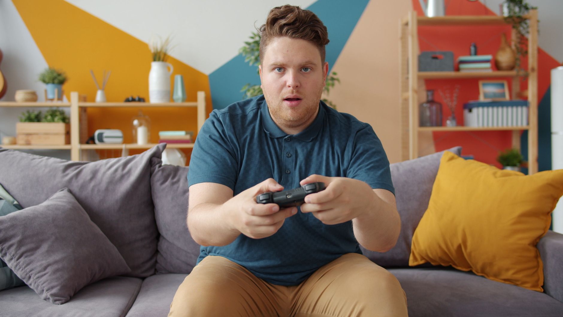 A young man intensely playing video games in a modern living room setting. — Blackjack Etiquette: Mastering Table Manners