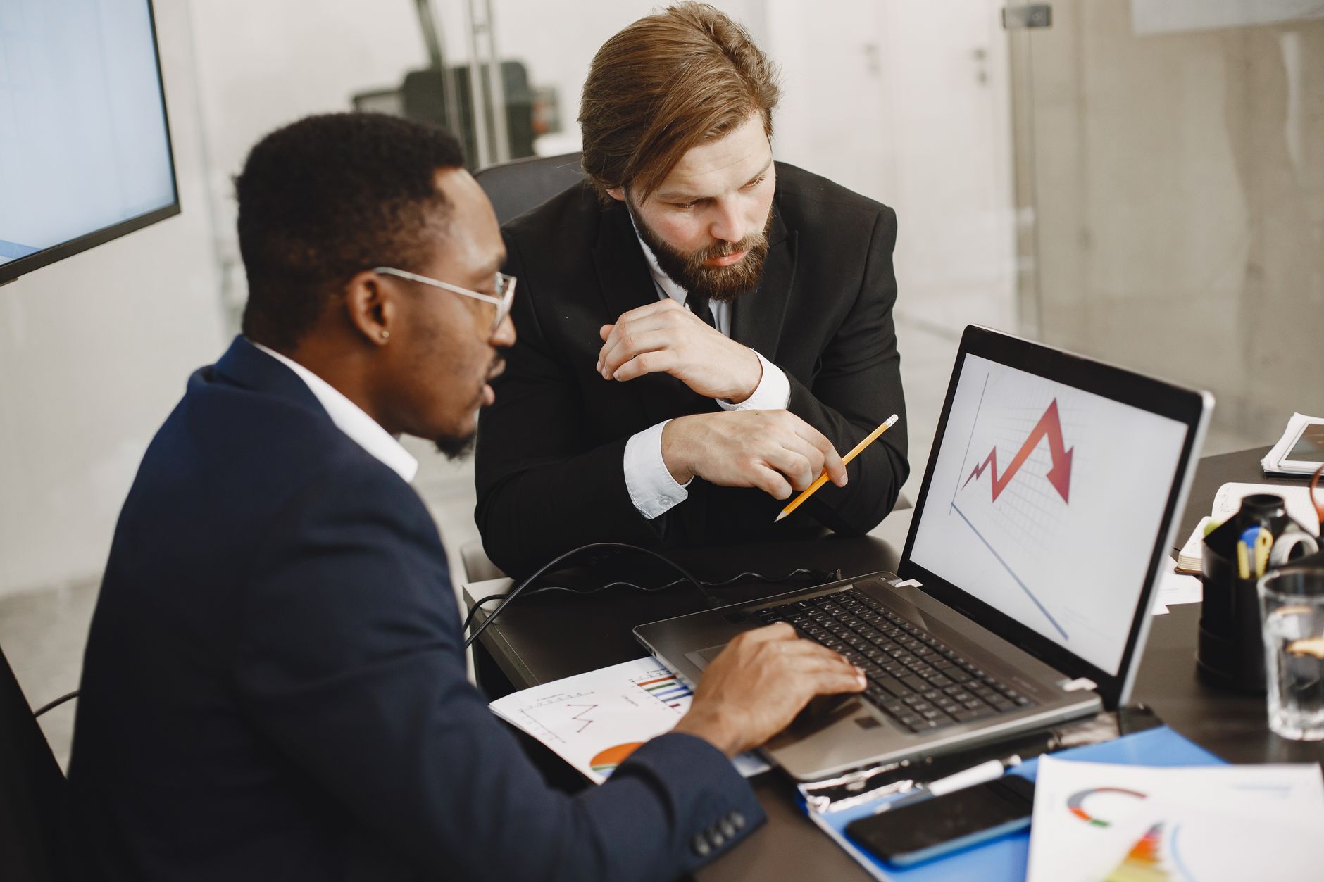 Two business professionals discuss marketing data on a laptop in a modern office. — Creating Buzz: How to Use Press Releases