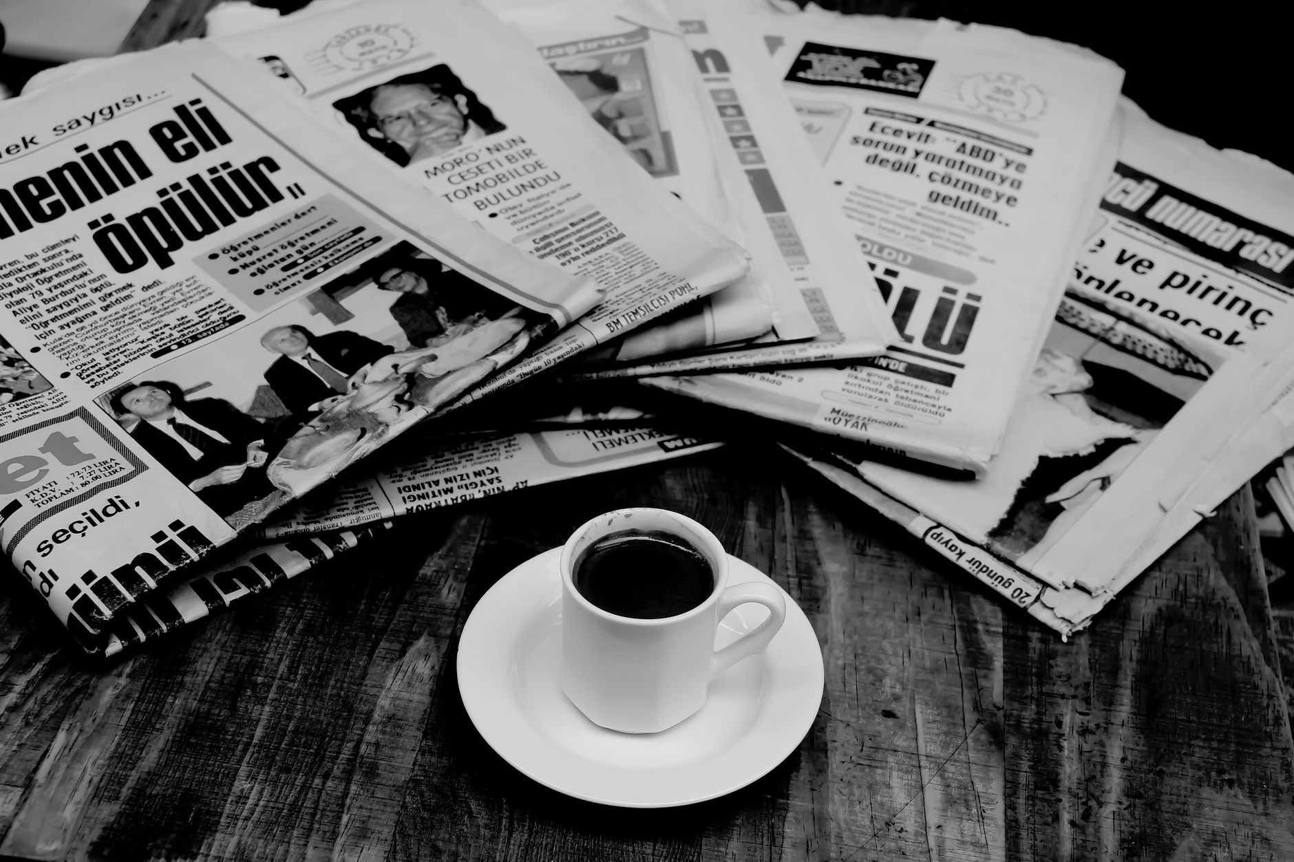 A cup of Turkish coffee sits on a wooden table next to a stack of newspapers. — Discover the Essence of Tantra: Tantric Massa