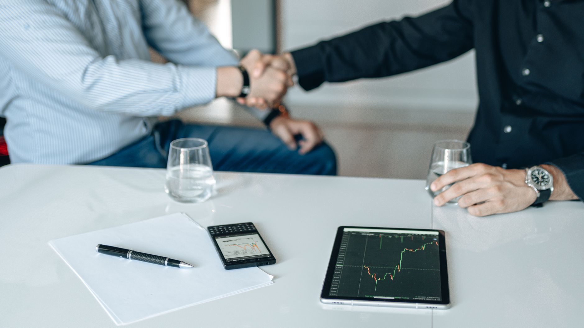Business meeting with handshake and financial analysis displayed on a tablet. — "Elevate Your Ride with Dominator Cycles' Evi