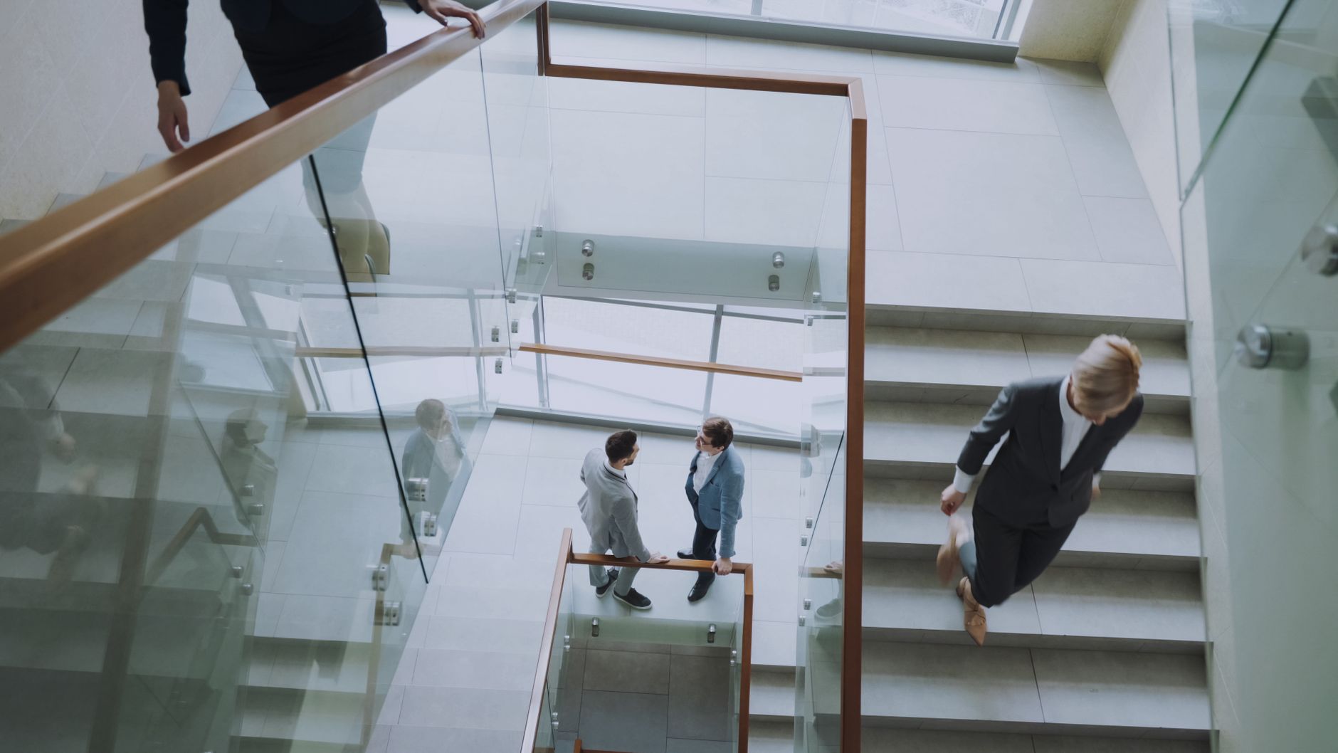 Aerial view of professionals conversing in a glass staircase in a modern office. — Enjoy Secure Private Toto Play with Mt-Pol