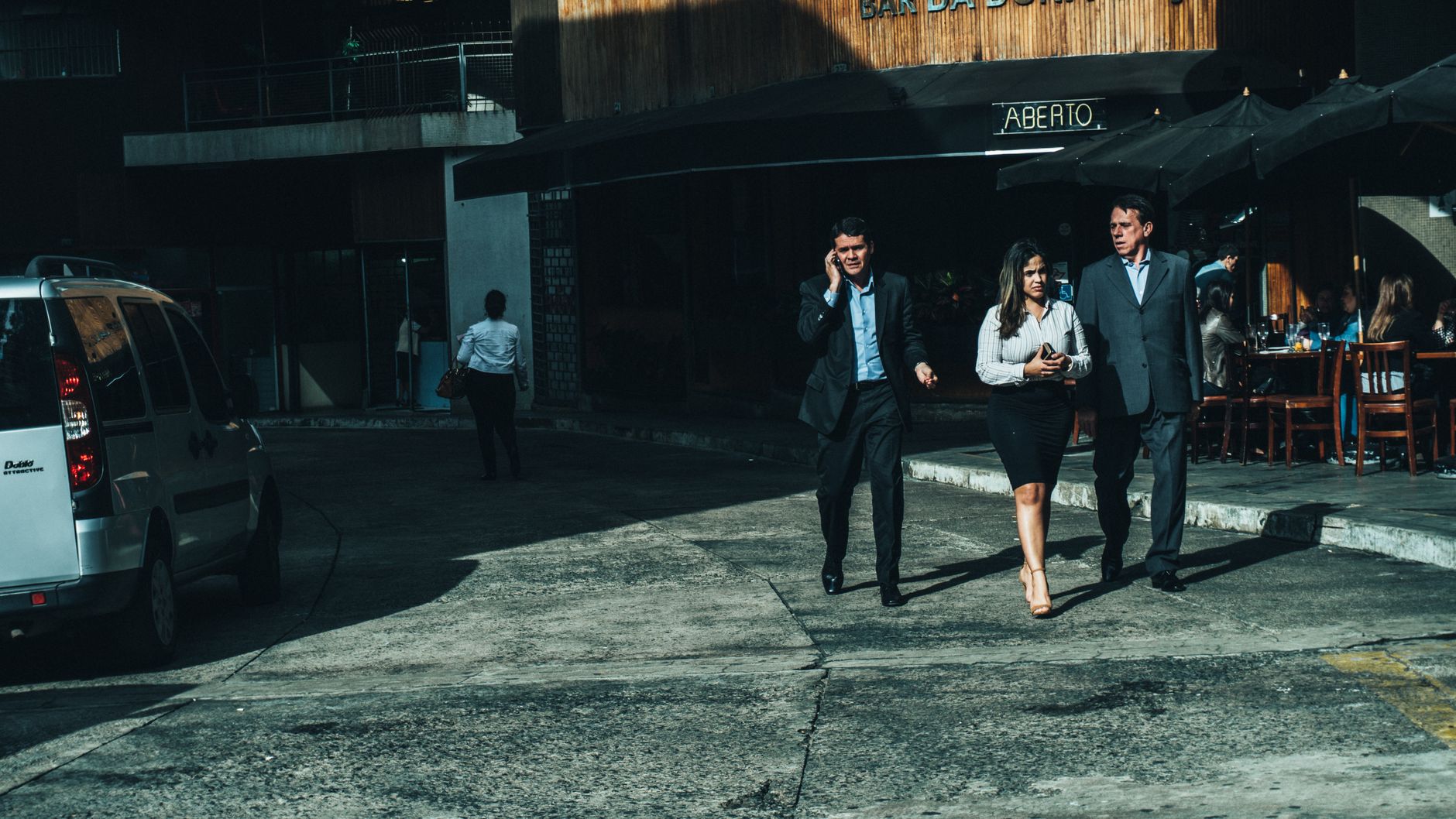 Three business professionals walk along a city street outside a cafe. — Exploring the Medical Uses and Effects of Codeine Pho