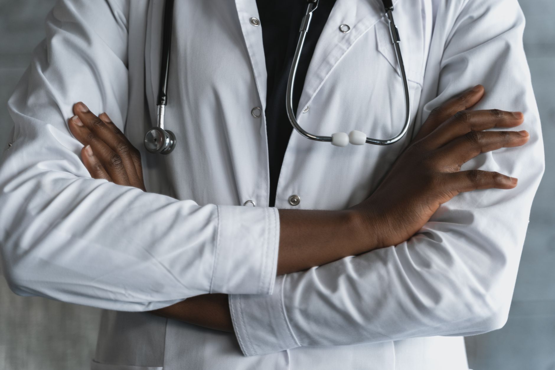Close-up of a confident doctor in a lab coat standing with crossed arms and stethoscope. — Health Economics Outcomes Research