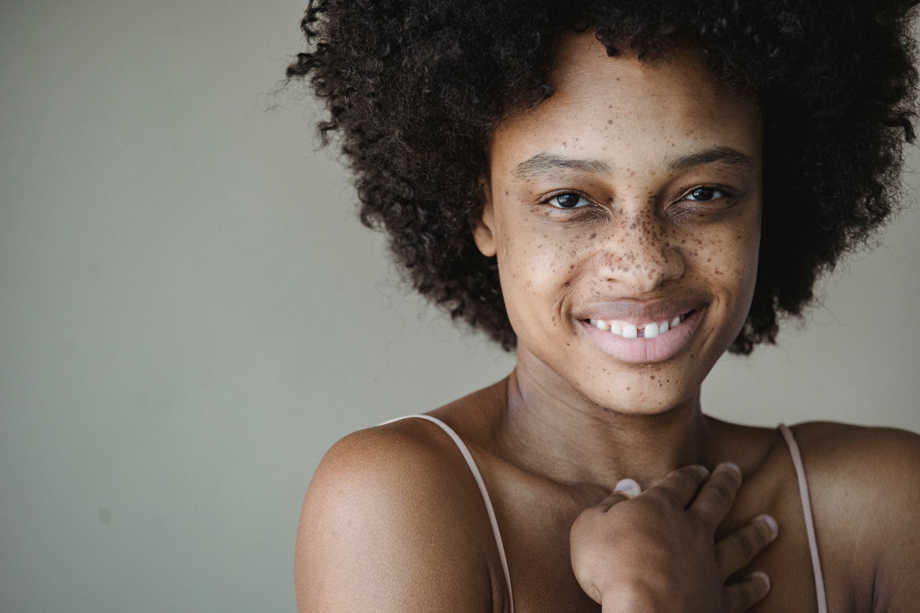 Close-up portrait of a smiling woman with natural afro hair and freckles, embracing natural beauty. — How Double Chin Liposuc