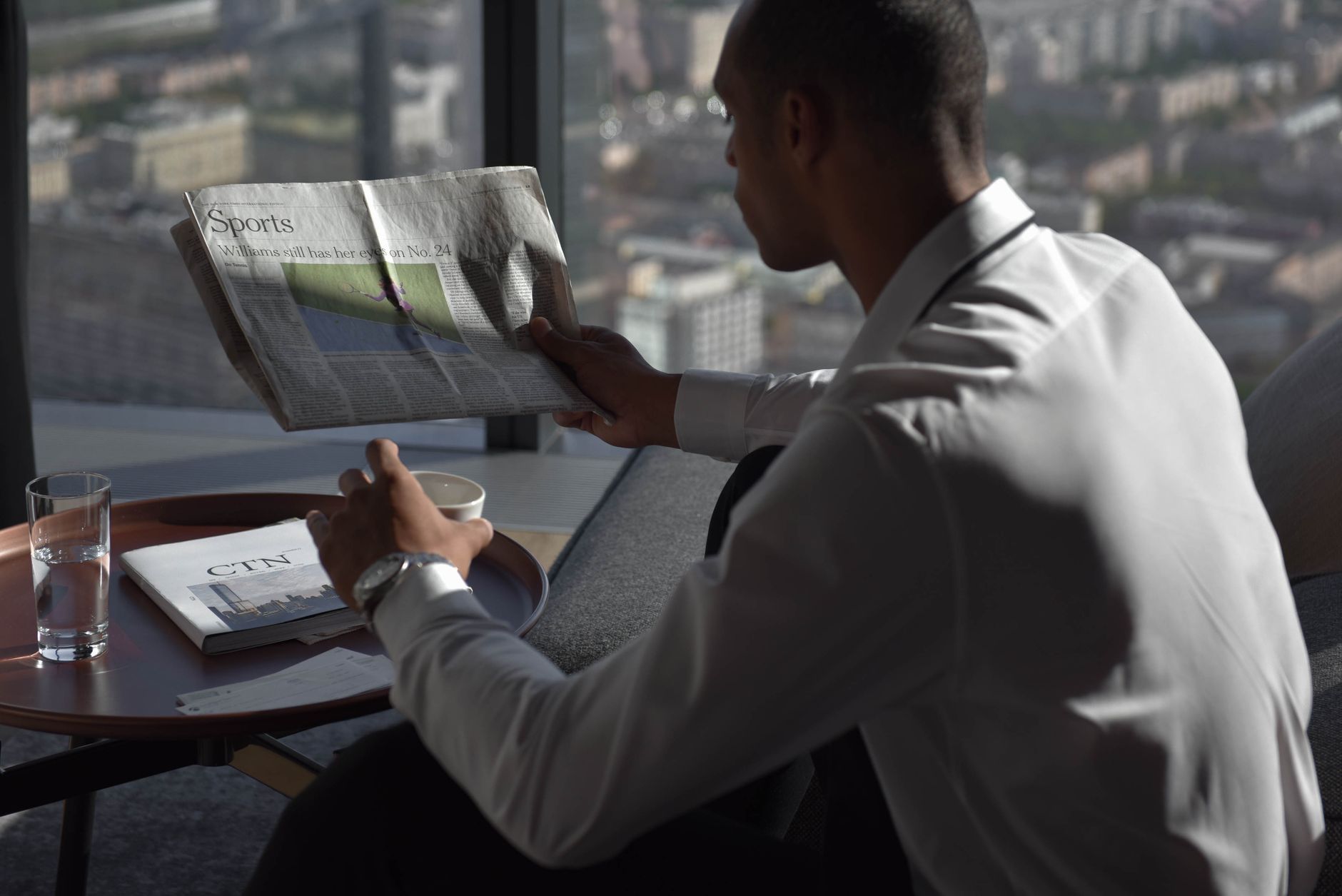 Businessman in office reading sports section, enjoying coffee with city view. — How to Detect Early Signs of Water Damage