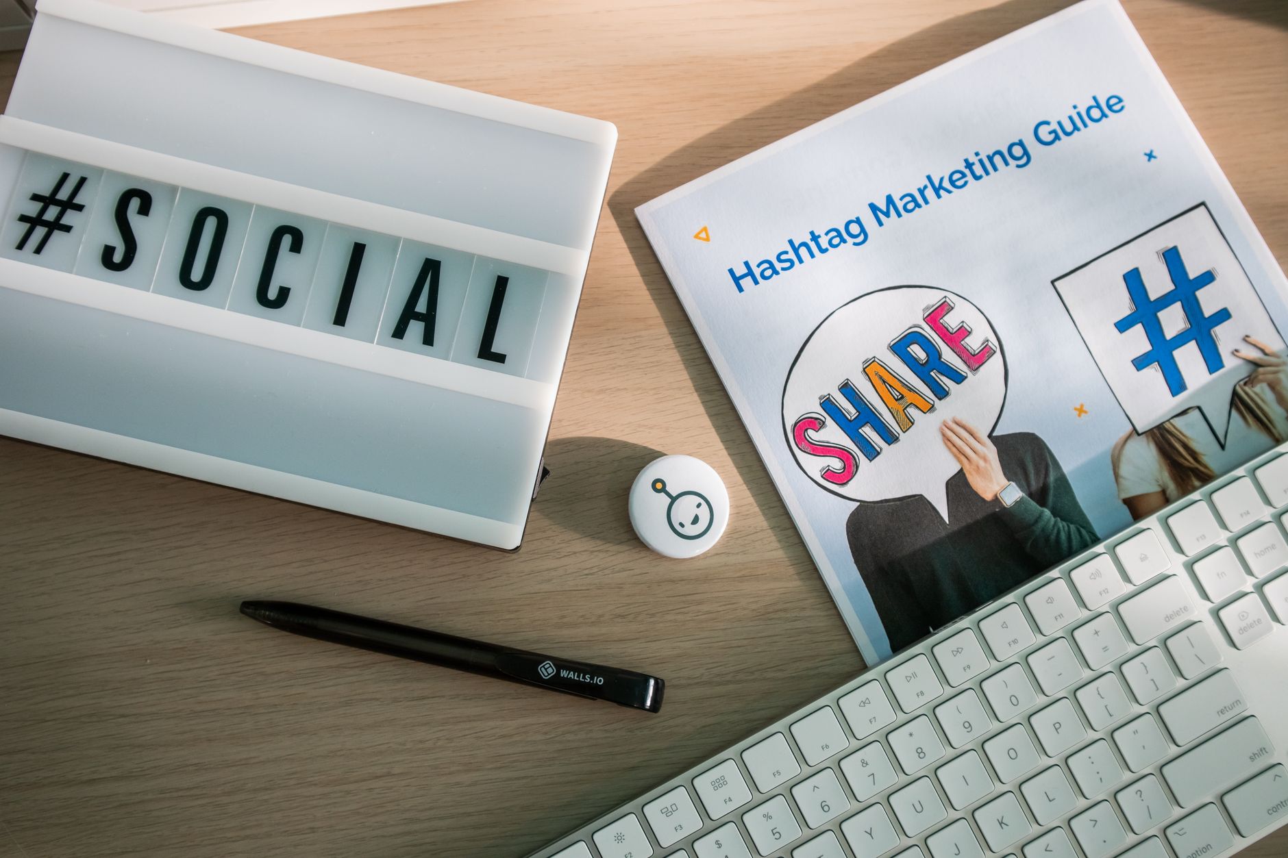 A desktop setup with social media marketing essentials including a keyboard, lightbox, and guide. — How to Improve Email Camp