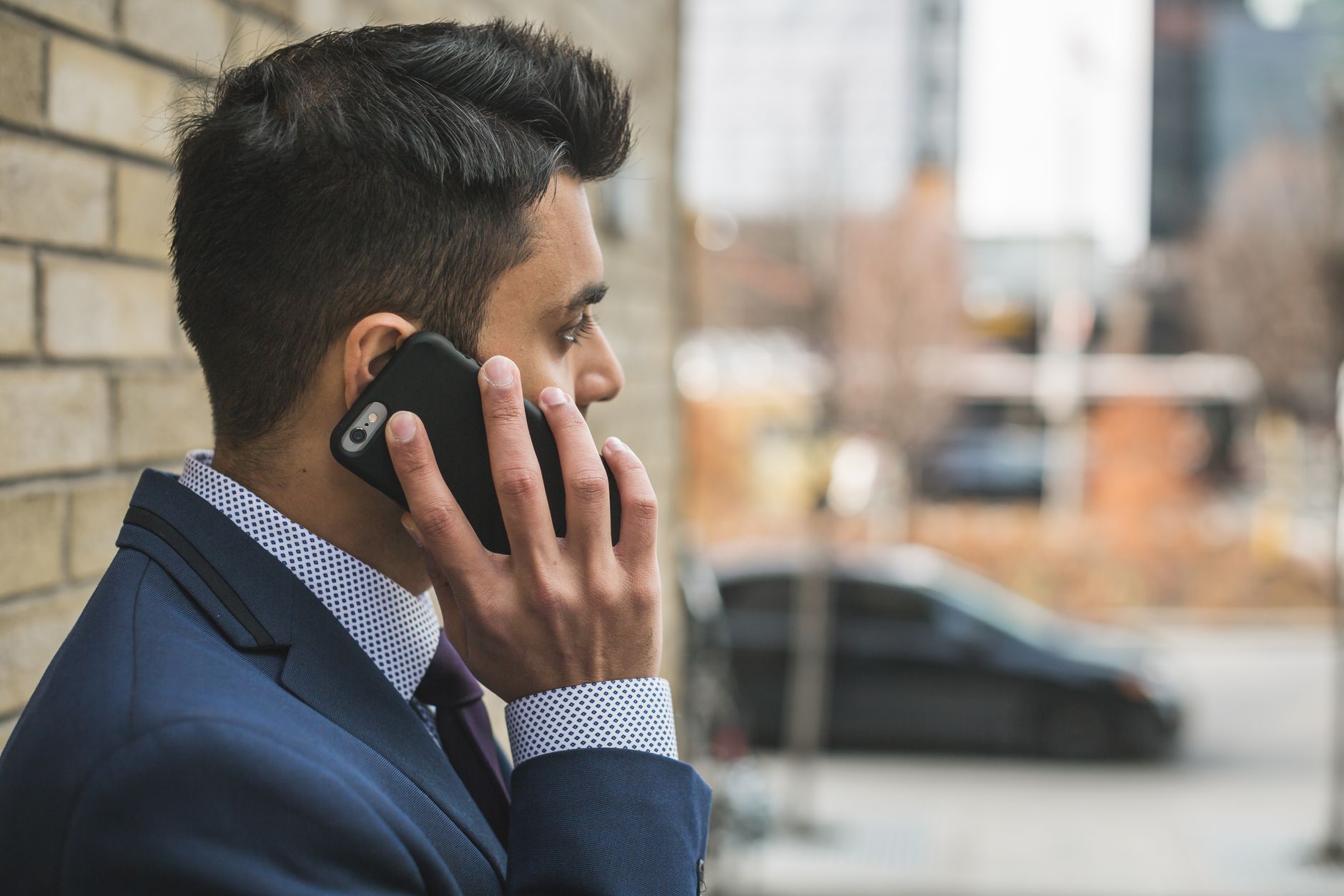 Professional man in suit making a phone call outside in city setting. — Navigating Complex Cases in Oral & Maxillofacial Surg
