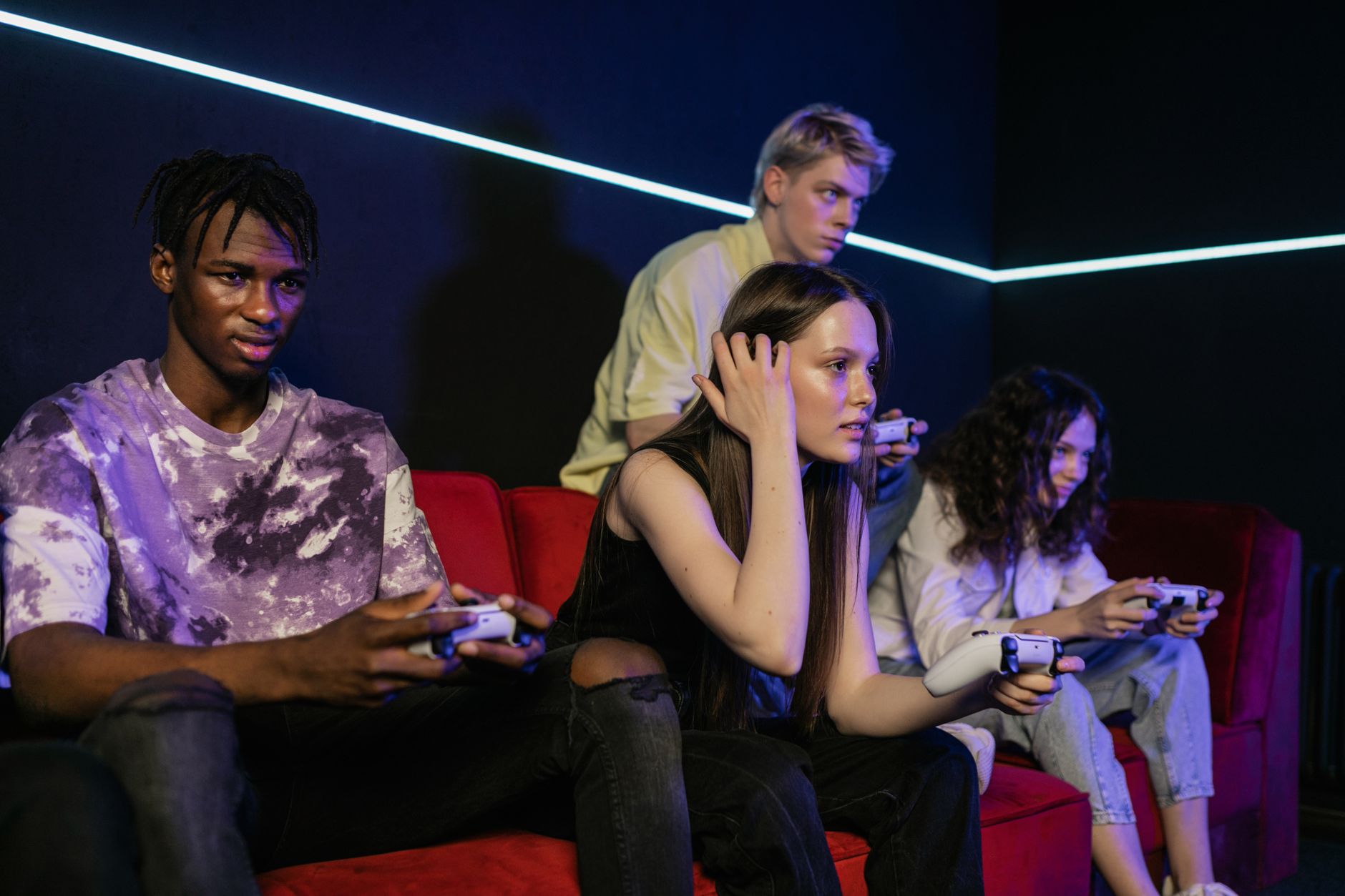Group of friends enjoying a gaming session on a red sofa with wireless controllers. — Slot Website: A Seamless Gaming Experie