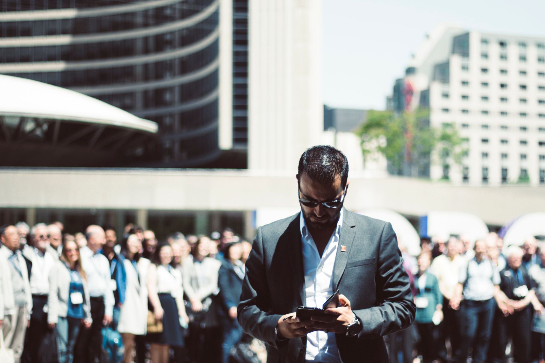 Focused businessman using tablet in a bustling crowd in Toronto's busy urban setting. — THC drink information about relaxatio