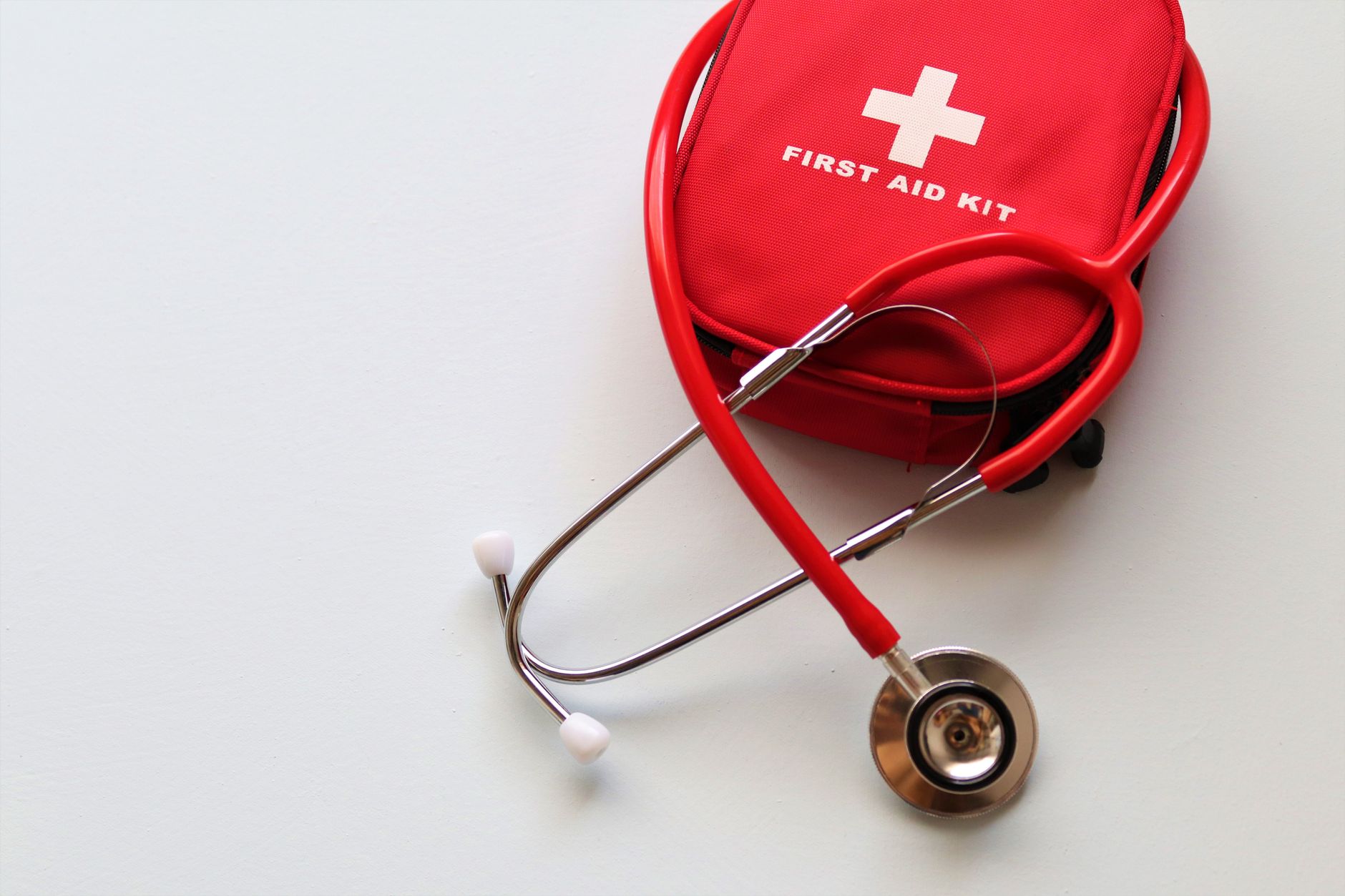 A red first aid kit paired with a stethoscope, signifying healthcare and medical treatment essentials. — The Role of Technolo