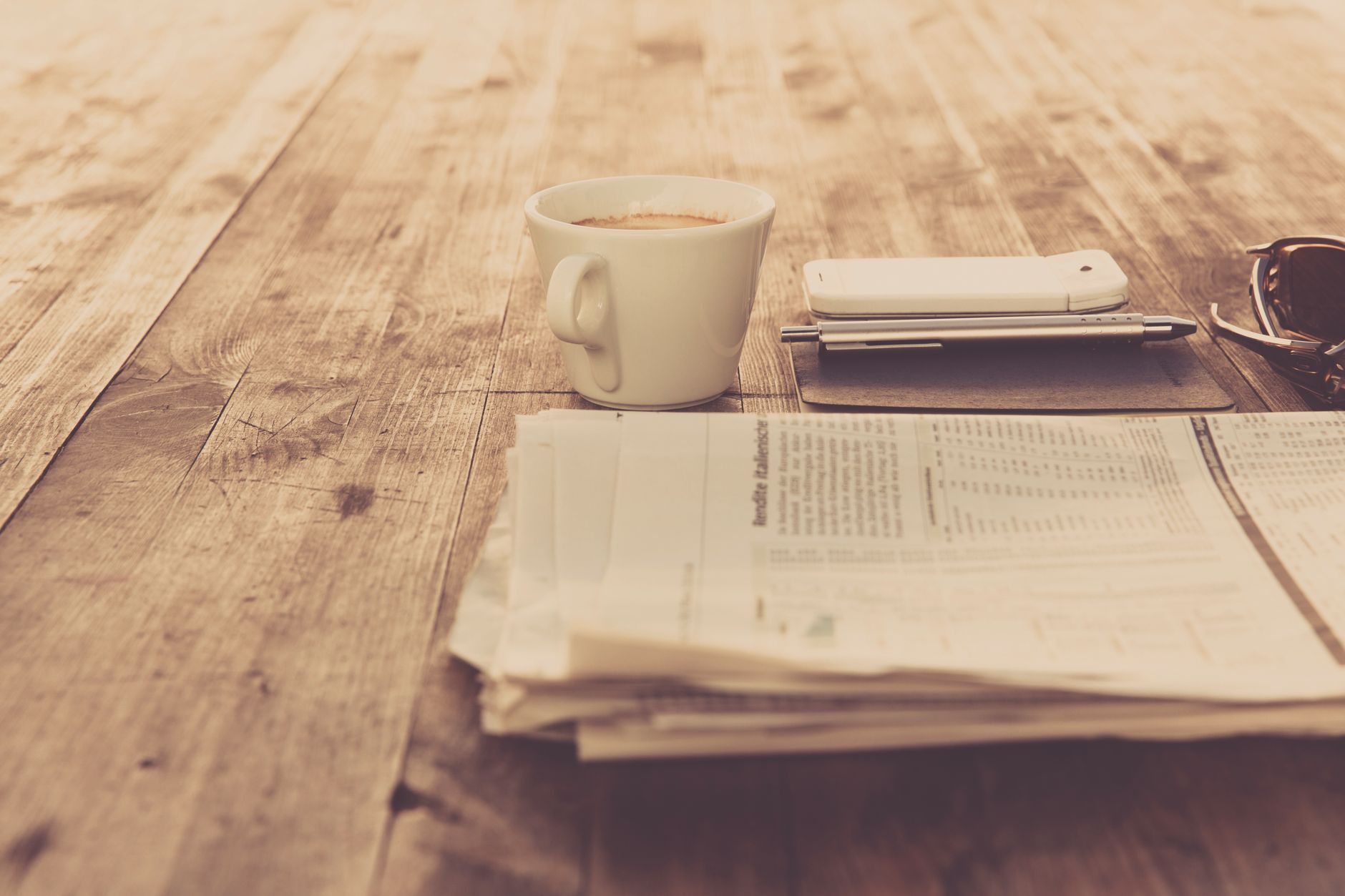 A warm vintage morning setup with coffee, newspaper, and smartphone on wooden table. — Transform Your Sound: Online Mastering